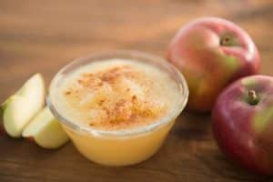 Compote de pommes dans un pot en verre, avec pommes autour